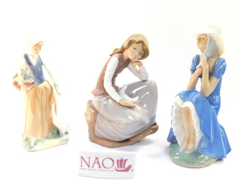 Three Nao porcelain figures, modelled as a seated girl wearing a bonnet, a girl with a goose and fruit, and a seated girl with a dove, together with a Lladro porcelain plaque. (4)