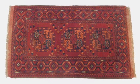 An Afghan rug, with a lozenge border and centre field with three panels, 120cm x 92cm.