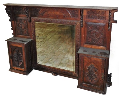 A carved oak overmantel, with central rectangular mirror frame and two cupboard doors, each with carved decoration, the top section 103cm high, 161cm wide, approx 32cm deep.