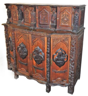 A continental oak serpentine sideboard, with various extensively carved panels doors and figures, with single key, 131cm high, 134cm wide, 62cm deep.