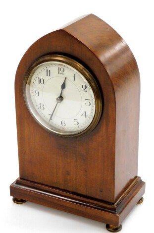 An Edwardian walnut cased lancet mantel clock, with small circular enamel dial, on a stepped base with brass button feet, 23cm high, 13cm wide, 8cm deep.