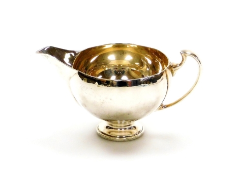 A small George V silver cream jug, with shaped spout on a curved handle, London 1934, maker's stamp EB, 5cm high, 2½oz.