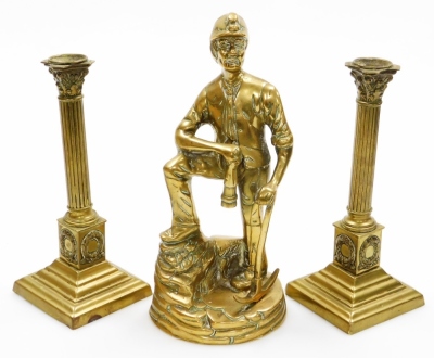 A pair of late 19thC brass Corinthian column candlesticks, 23cm high, and a cast brass figure of a Miner, 27cm high. (3)