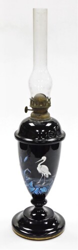 A Victorian opaque glass oil lamp, the oil lamp base on a black finish with painted detailing of blue leaves and flowers with a white stalk and gilt banded stepped base with detachable top oil lamp section, 50cm high.