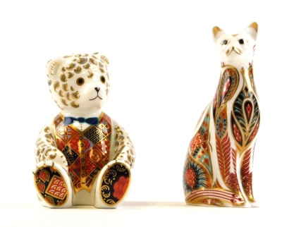 Two Royal Crown Derby paperweights, to include a cat with red stamp numbered LIX with silvered button and a seated teddy bear labelled LX11 with silvered button, 13cm and 12cm respectively.