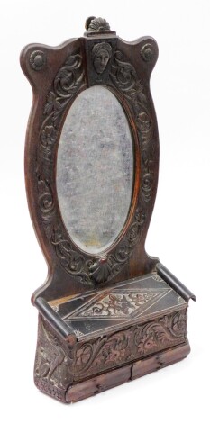 A late 19thC carved oak wall mounted mirror shelf, the curved top above Medussa head and shell carving, with box bottom and two single drawers, 62cm high, 31cm wide, 8cm deep.