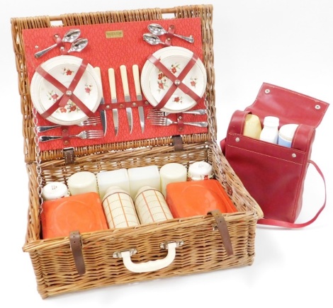 A Brexton wicker picnic basket and contents, comprising metal food tins, carry flask case, thermoses, replacement cutlery, etc.