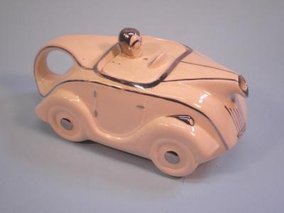 A 1930's novelty teapot in the form of a cream glazed racing car with silvered borders