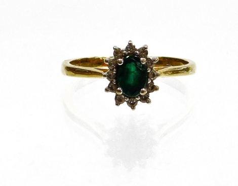 An 18ct gold emerald and diamond cluster ring, the central emerald set with four claws surrounded by tiny diamonds, ring size Q, 2.8g all in, boxed.