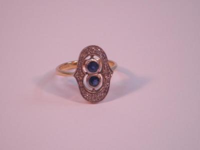 An 18ct Art Deco period plaque ring with two small round sapphires surrounded