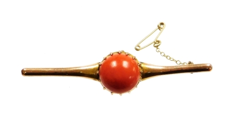 A 9ct gold coral set bar brooch, the large circular coral cabochon in a claw setting, 1.6mm wide, 9.2mm deep, the coral with pierced back, on a plain design brooch, on a steel pin back and safety chain, 7cm wide, 8.7g all in, boxed.