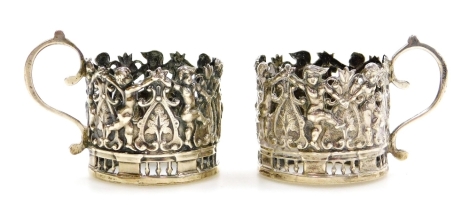 A pair of novelty silver cup cases, each depicting cherubs and flowers, London 1911, 2.5cm high, 1oz.