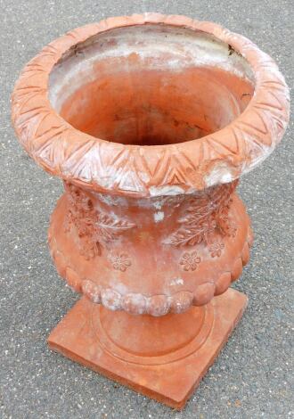 A terracotta urn vase, with dart moulding and applied floral detailing, on a square base, 54cm high.