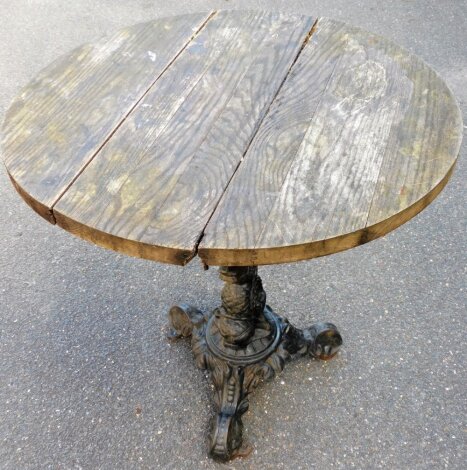 A cast iron based pub table, with three slat wooden top, on a tripod cast iron base, 70cm high, 72cm diameter.