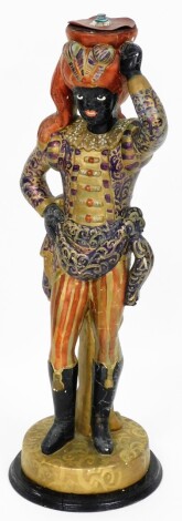 An early 20thC painted plaster Blackamore figure, possibly from an earlier table base or lamp, the figure in gold and purple overall dress, Eastern inspired on a stepped and stained base, 80cm high.