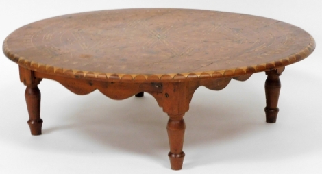 An Eastern inspired pine coffee table, the circular design top with various parquetry and mother of pearl inlay, 86cm diameter, on a pine square base, with tapered legs, the base 24cm high.