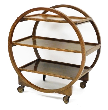 An Art Deco three tier tea trolley, the sides shaped as a circle holding three shelf section on castors, 78cm high, 74cm wide, 43cm deep.