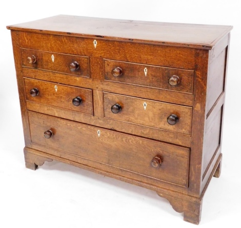 An early 19thC oak Lancashire chest, of four short and one long drawer, lift top two drawers dummy, with mother of pearl escutcheons and knob handles, on a stepped and shaped base, 100cm high, 124cm wide, 52cm deep.