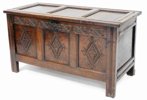 An early 18thC carved oak coffer, with three panel top and three panel front section above lozenge carved frieze, raised on stiles, 61cm high, 113cm wide, 49cm deep.