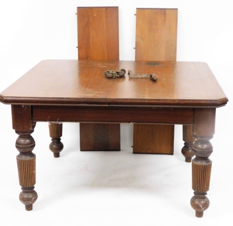 A late Victorian mahogany wind out dining table, the canted top raised on heavily carved reeded tapering legs, terminating in compressed bun and cylindrical feet, when closed 71cm high, 117cm wide, 106cm deep, with winder.