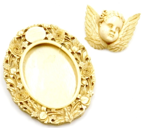 Two ivory trinkets, to include an early 19thC ivory circular photograph frame, with pierced rose and flower decoration, 9.5cm x 8cm (AF), together with a similar period cherub brooch, on steel pin back, 6cm wide, 4cm high. (2)