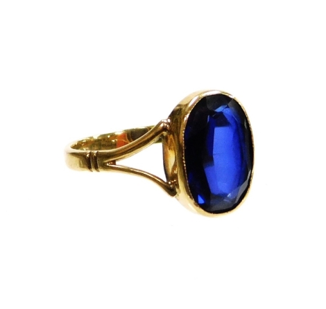 A stone set dress ring, with an oval set blue paste stone, in rub over setting with V splayed shoulders, yellow metal stamped 9c, ring size S, 3.3g all in, boxed.