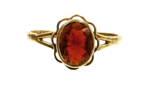 A 9ct gold dress ring, set with oval cut citrine, in a rub over setting with pleated flower border, on two splay shoulders, ring size S, 2.6g all in.