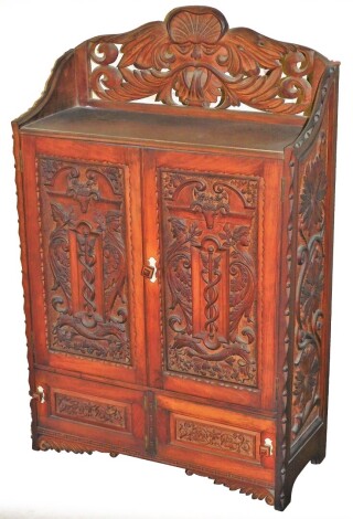 A Victorian carved oak wall cabinet, with mask head gallery top, two cupboard doors depicting male and female figures with rams head, with a two cupboard base, 72cm high, 51cm wide, 21cm deep.