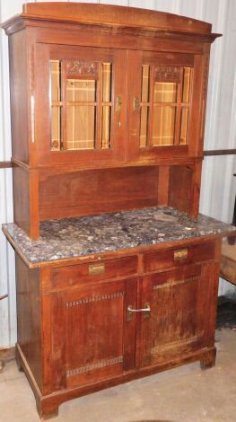 A carved oak kitchen dresser, the dresser top with two astragal glazed doors with engraved fruits of the forest panels, on Eastern style brass handles, with a marble effect top above two drawers and two cupboard door base, 206cm high, 124cm wide, 60cm dee