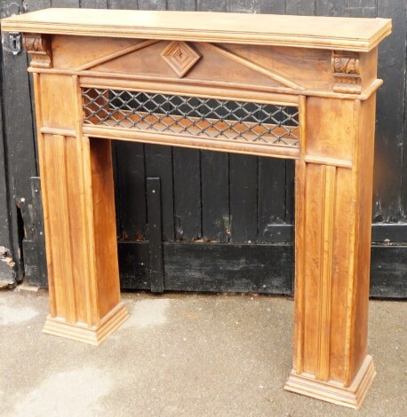 An oak fireplace surround, with carved leaf finials and metal cross section, on two plinth columns, 125cm high, 125cm wide, 31cm deep.