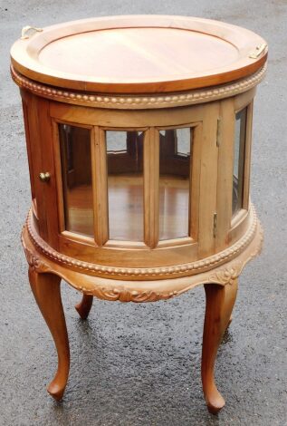 A Continental display table, the circular tray top raised above an all round glazed section with hinged openings, on cabriole legs with a beaded outline and shield and scroll carvings, 82cm high, 50cm diameter.