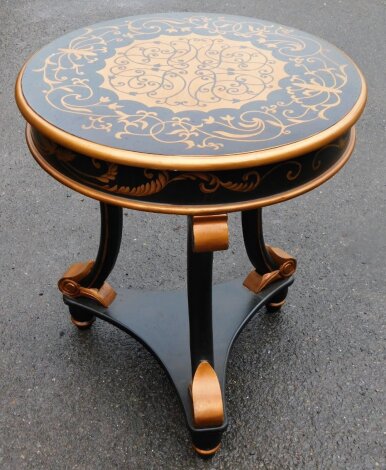 A French style painted circular side table, in gold and black, on tripod scroll base, 70cm high, 60cm diameter.