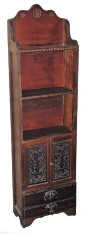 A narrow oak bookcase, the top section with three carved shelves above Medusa carved cupboard door section with two drawer base, 140cm high, 38cm wide, 19cm deep.