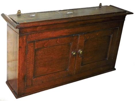 An early 19thC oak wall cabinet, with single shelf and two cupboard doors with brass handles above cornice, 60cm high, 105cm wide, 23cm deep.