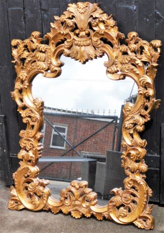 A modern gilt framed wall mirror, the arched top with feather and leaf scroll decoration, 127cm high, approx 90cm wide.