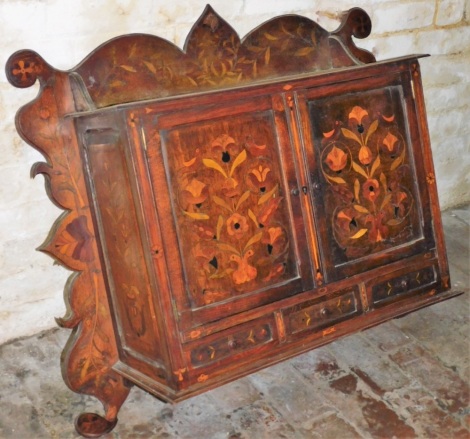 An early 19thC Dutch marquetry wall cabinet, with carved frieze and marquetry inlay of birds and flowers with two cupboard doors and three drawers, 76cm high, 92cm wide, 33cm deep.