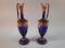 A pair of Venetian blue glass ewers each decorated in colour enamels and gilt with flowers