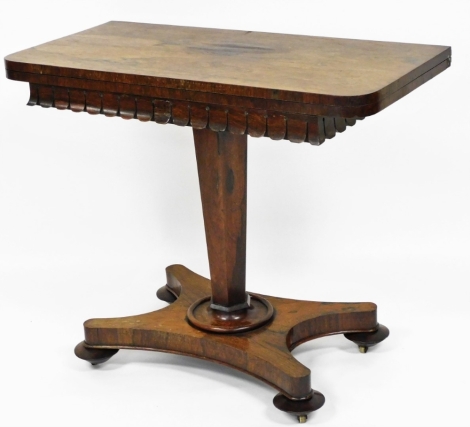 A late 19thC rosewood card table, opening to reveal a red lined interior, on fret carved top on a tapered stem, quatrefoil base with castors, 76cm high, 91cm wide, 44.5cm deep.