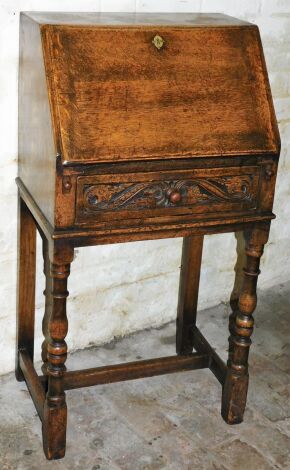 A carved oak bureau on stand, the fall top opening to reveal letter section above single drawer on turned legs, 115cm high, 53cm wide, 38cm deep.