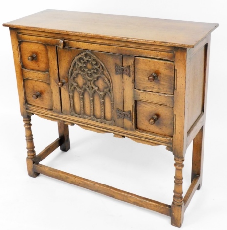 An Ercol style oak credence cabinet, with four dummy drawers and carved cupboard centre, rectangular base, 84cm high, 91cm wide, 35cm deep.