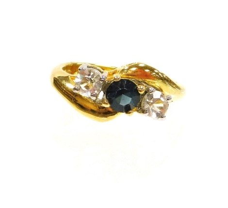 A crossover dress ring, claw set with white and blue stones, on a fancy part pierced base metal shank, ring size N.