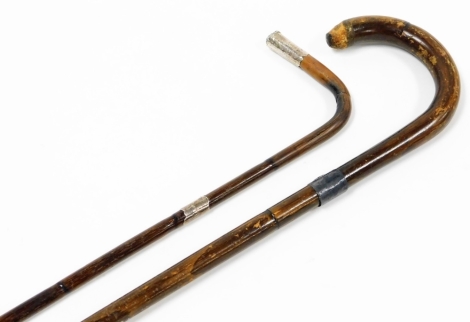 Two ebony and silver capped walking canes, one with silver collar, the other silver collar and terminal, 87cm high and 80cm high respectively.