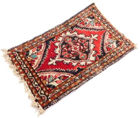 A Persian rug, with medallion border and central medallion panel, on tassel ends, 61cm x 39cm.