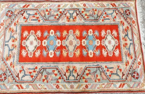 A Middle Eastern cream and orange ground rug, with floral bordering and five central floral medallions, on tassel ends, 191cm x 123cm.