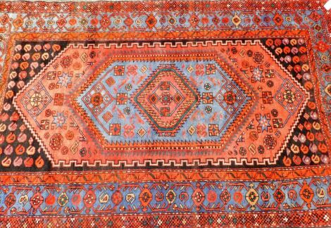 A Middle Eastern carpet, on a red ground with blue medallion border on a central single medallion central panel, on white tassel ends, 224cm x 134cm.