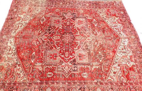 A middle Eastern red ground rug, with medallion border and central Greek key style medallion, with cream, red, and green design, with tassel ends, 348cm x 286cm.