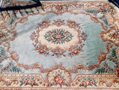 A large wool cut carpet, on a cream ground with turquoise bordering and tassel ends, 366cm x 280cm.