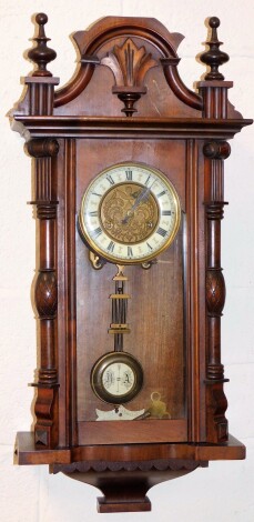 A late 19thC walnut cased Vienna wall clock, the moulded cornice top above two reeded columns, with pendulum and key, 74cm high, 30cm wide, 16cm deep.