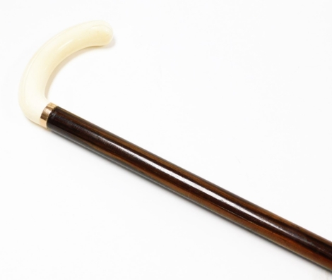 A 1910/1920's ivory handled walking stick, with curved handle on a yellow metal collar, unmarked on mahogany cane, 88cm long.