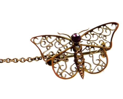 A butterfly brooch, the wings of filigree detailing, the body set with garnet and seed pearls, with safety chain, yellow metal, unmarked, 2.5cm wide, 2.5g all in.